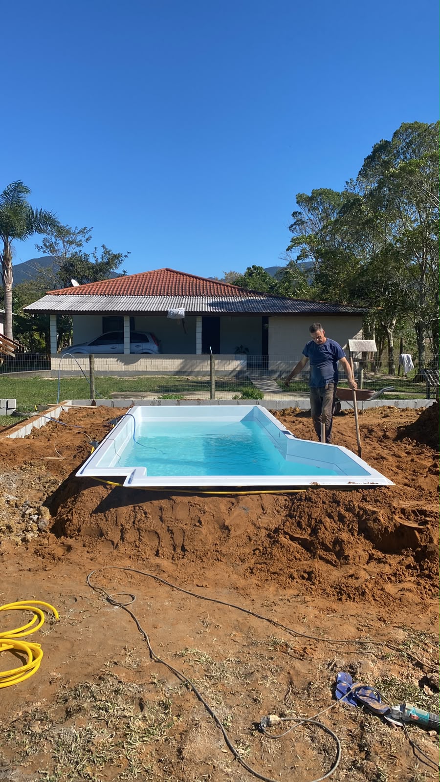 Obra de instalação de piscina em andamento com profissional trabalhando no terreno