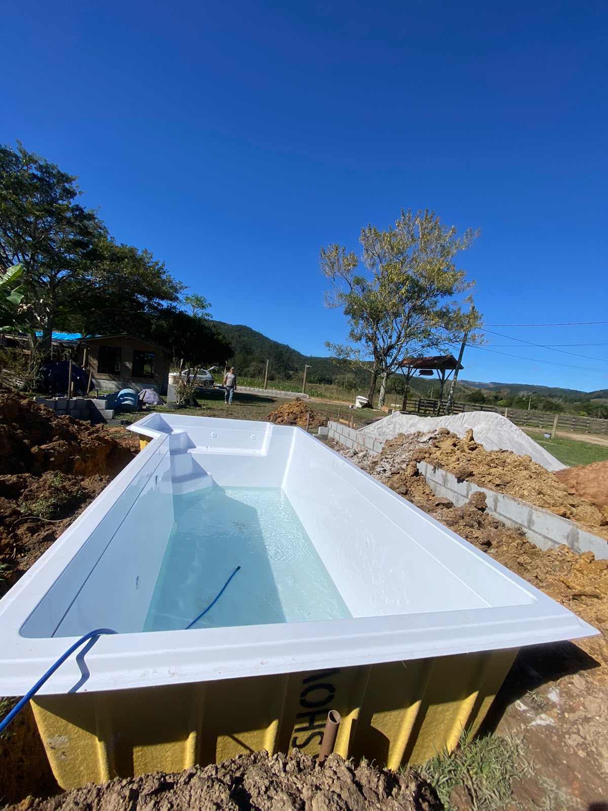 Piscina de fibra de vidro branca em fase de instalação no terreno